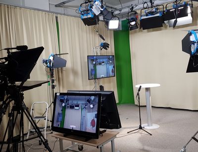 Ein Blick in das TV-Studio mit aufgebauten Scheinwerfern, Monitoren und Kameratechnik.